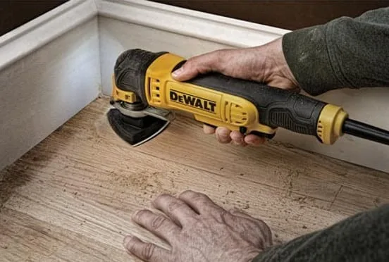 Corded oscillating multi-use tool sanding a wooden floor.